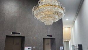 A modern lobby with a large chandelier, two elevators, and a fire extinguisher. - A comfortable house,  Dongdaemun History & Culture Park Station (Seoul)