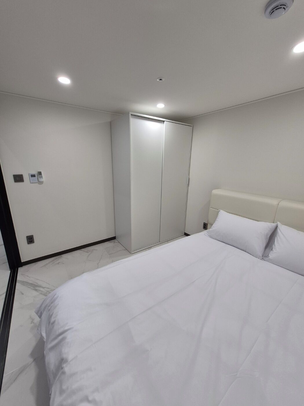 Une chambre d’hôtel moderne avec un grand lit, une armoire et un miroir.