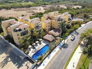 A residential complex with multiple buildings, a swimming pool, and a road.