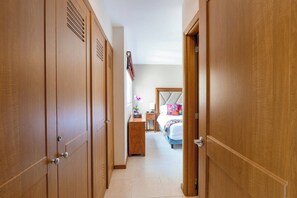 A hallway leading to a bedroom with a bed, dresser, and a nightstand.