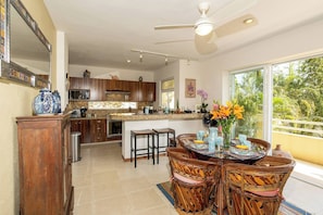 A spacious kitchen with a central island, wooden cabinets, and a dining area with wicker chairs.
