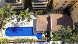 A multi-story residential building with a swimming pool, palm trees, and a red-tiled roof. - Sleeps 6, Views & Beach 1 Block (Nuevo Vallarta)