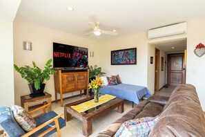 A living room with a sofa, a coffee table, a TV, and a ceiling fan.