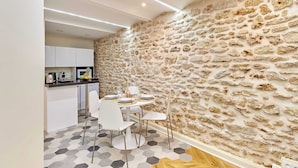 Una cucina moderna con mobili bianchi, un piano di lavoro nero e un'area pranzo con sedie bianche e un tavolo rotondo.