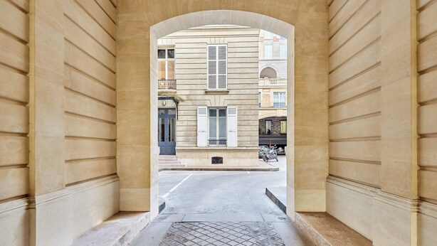 Un arco in pietra che dà su una strada con edifici sullo sfondo.