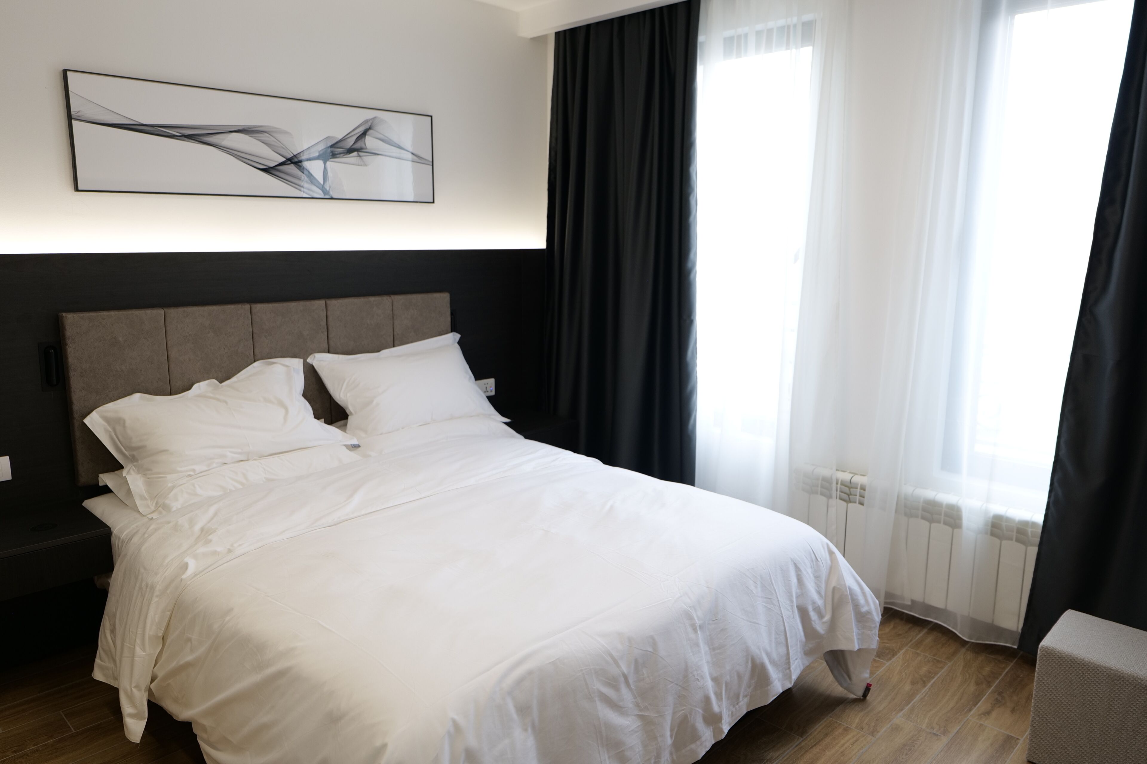 A neatly made bed with white linens in a modern hotel room.