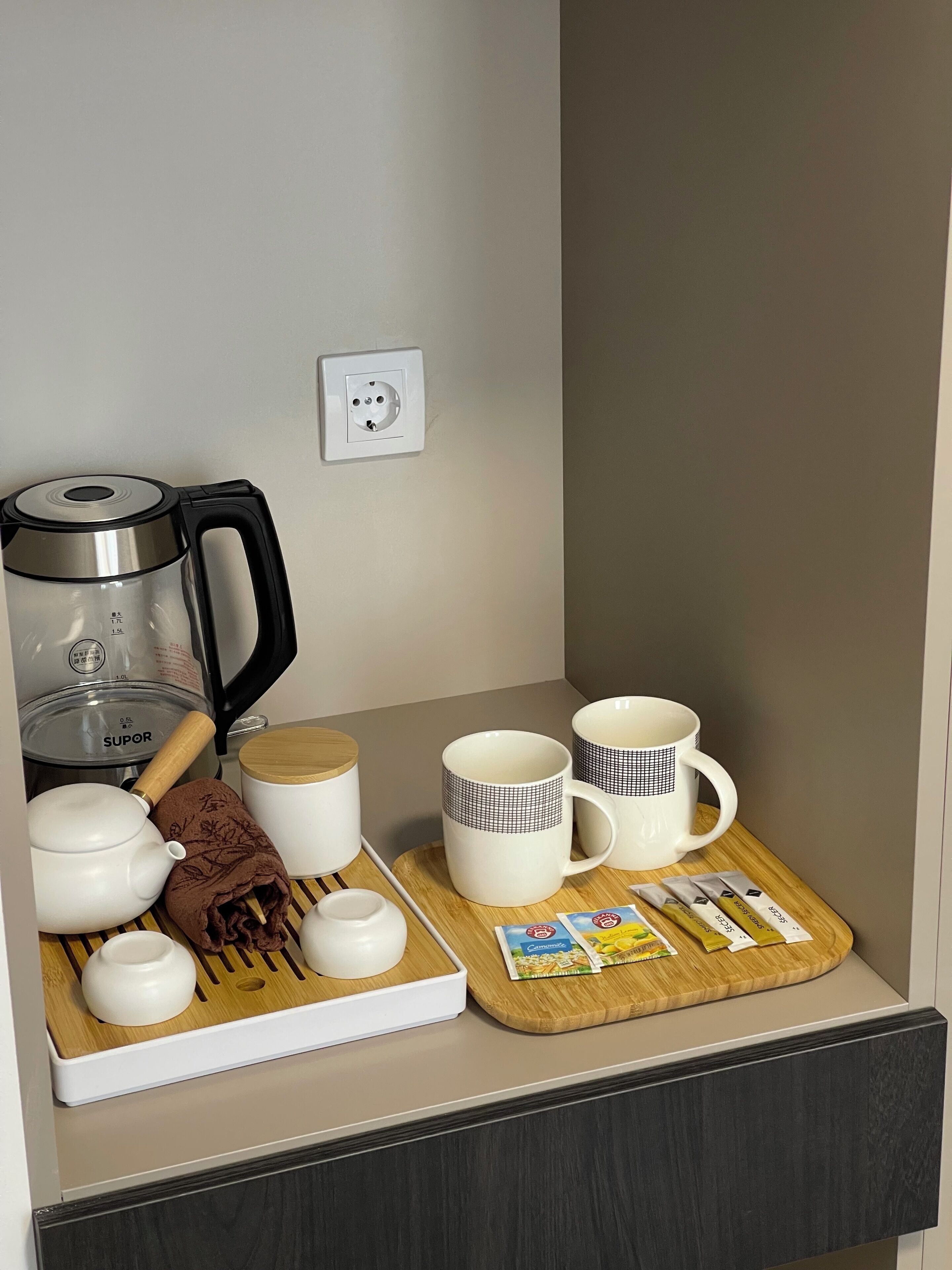 A kitchen counter with a coffee maker, teapot, cups, and tea packets.