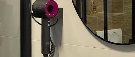 Un baño con un lavabo negro, un espejo y un secador de pelo sujeto a la pared.