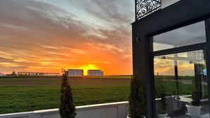 A modern building with large windows overlooking a sunset over a green field. - KIMMIY HOTEL (Belgrade)