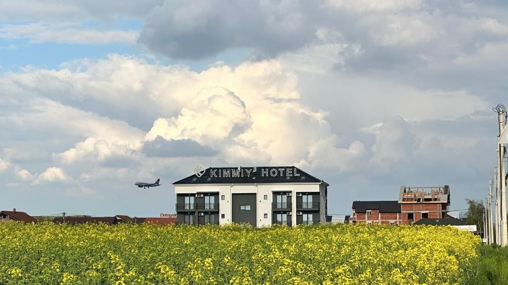 A modern hotel with a flat roof and a sign reading "KIMMY HOTEL" in the center.