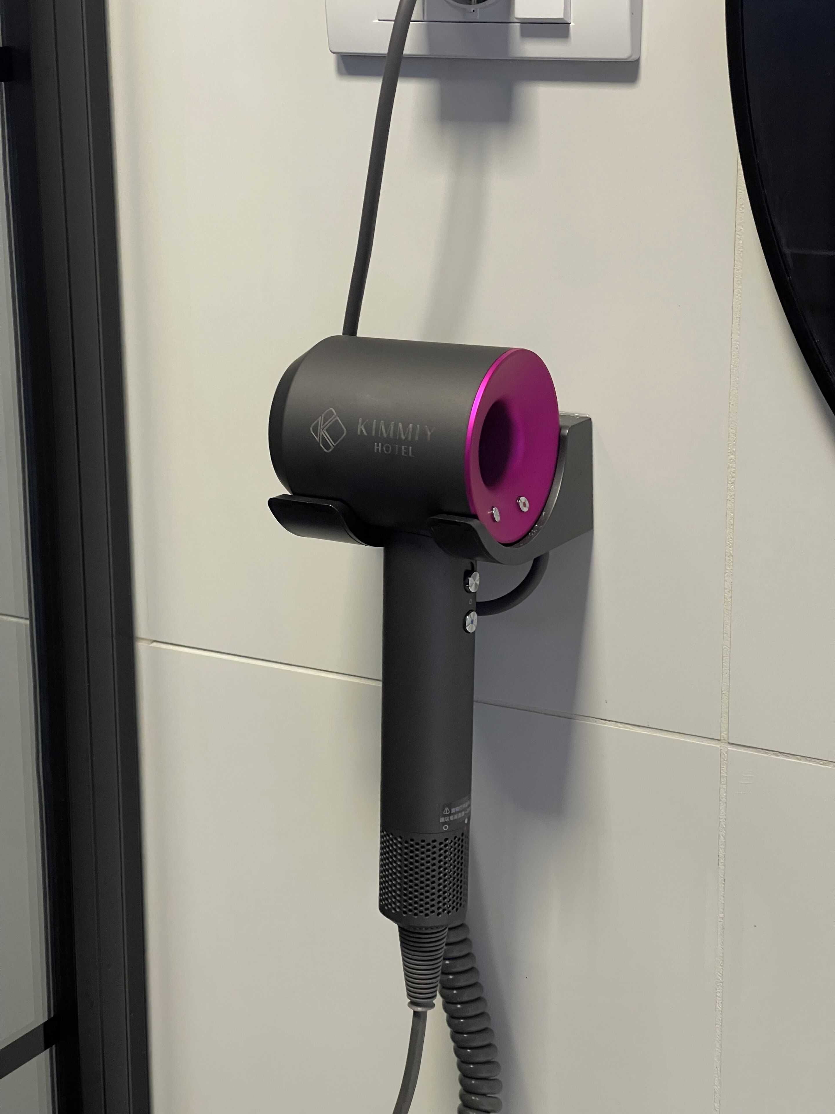 A hair dryer mounted on a wall with a cord.