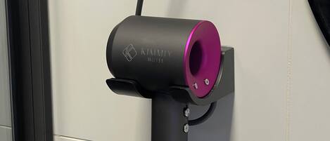 A hair dryer mounted on a wall with a cord.