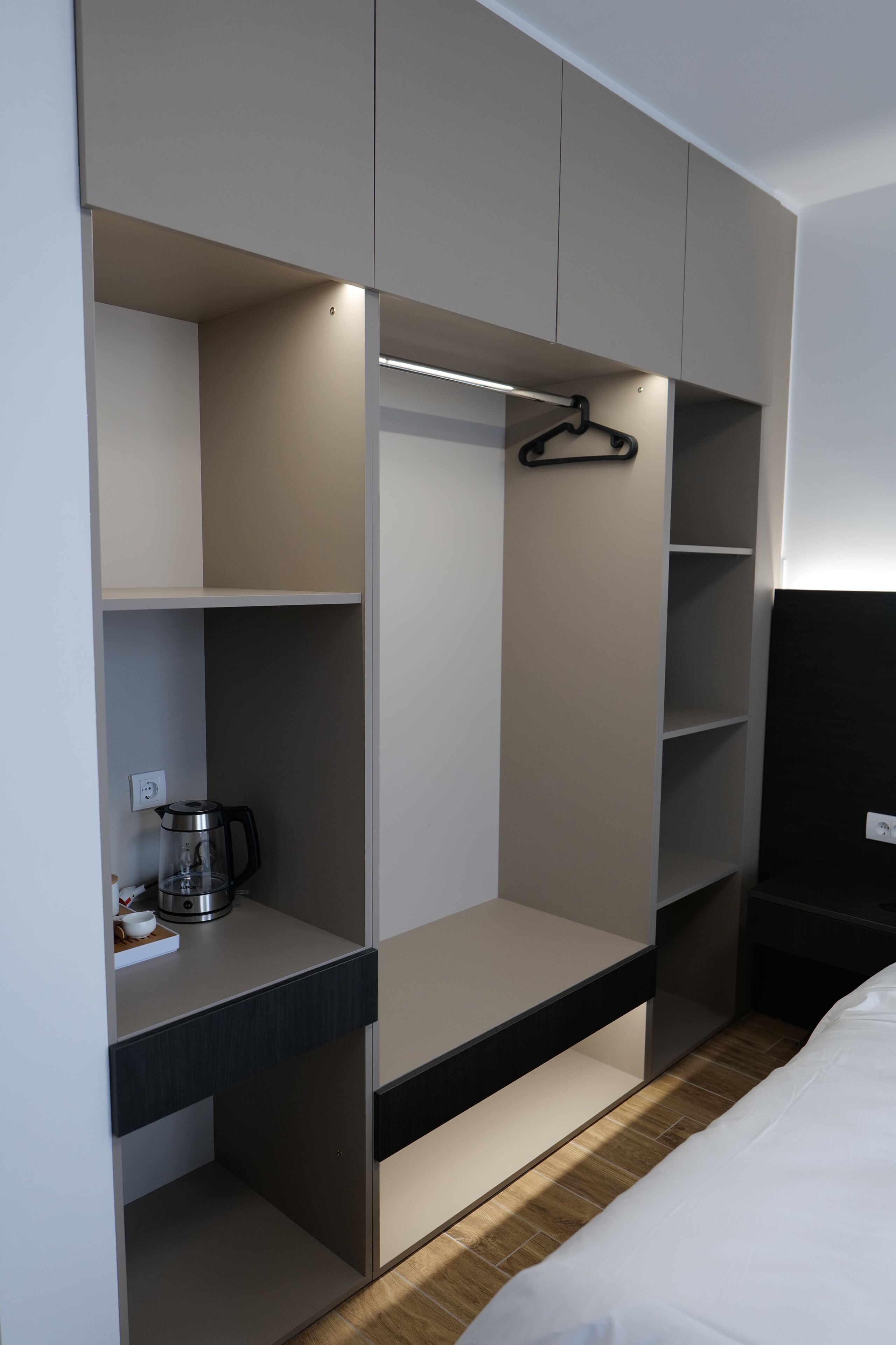 Un dormitorio moderno con armario empotrado, mesita de noche y lámpara colgante.