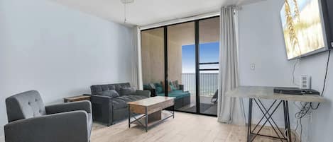 A modern living room with a sofa, armchairs, a coffee table, and a TV mounted on the wall.