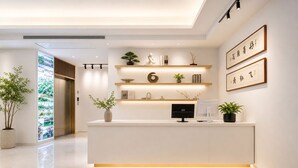 A modern reception desk with a minimalist design, featuring a flat-screen monitor, a potted plant, and a shelf with decorative items. - Mount Huangshan Danqing Yayuan B&B Hotel (Huangshan)