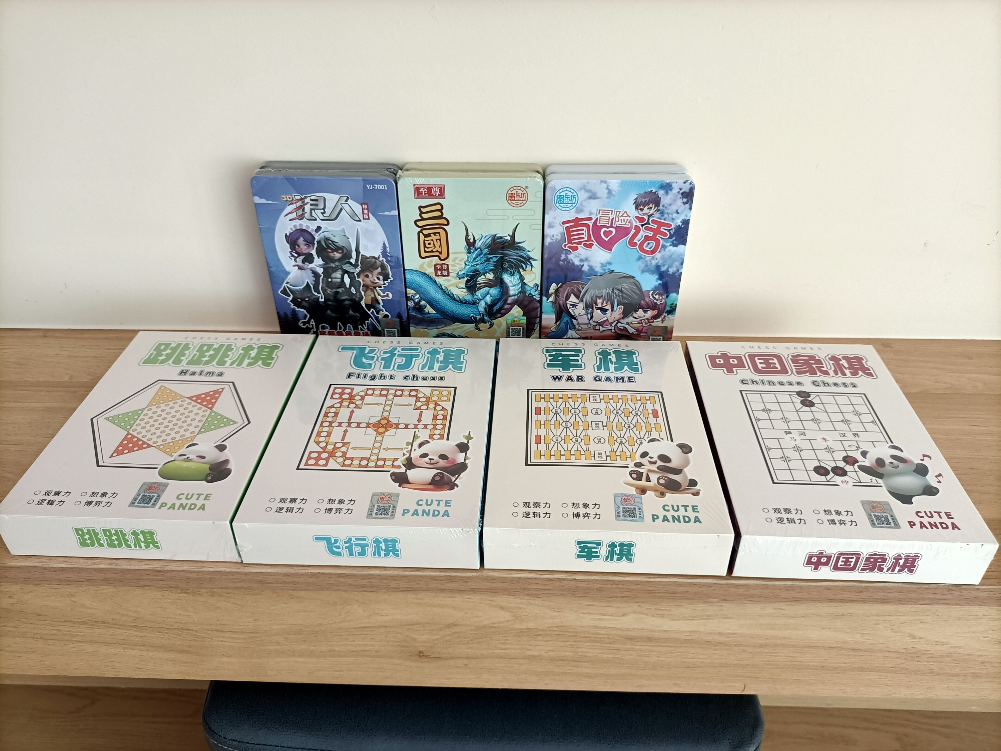 Four board games with Chinese text and panda illustrations on a wooden table.