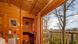 A wooden cabin with a cozy interior, a dining area, and a view of the surrounding landscape. - Pet-friendly Chalet in Surlingham, No Deposit (Norwich)