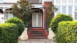 Una casa con puerta blanca, fachada de ladrillo y entrada empedrada.