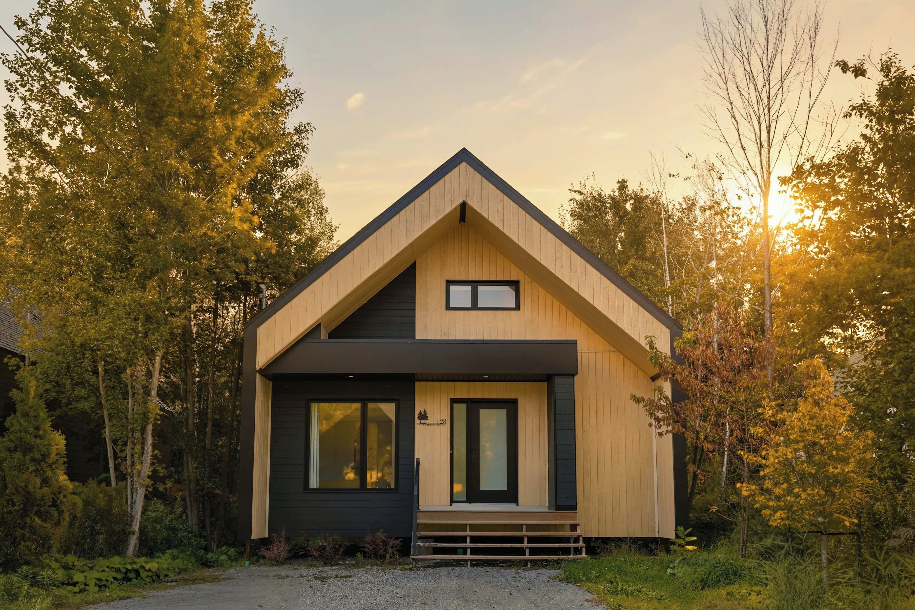 Une maison moderne à deux étages, dotée d’un toit à pignon, de grandes fenêtres et d’un porche à l’avant.