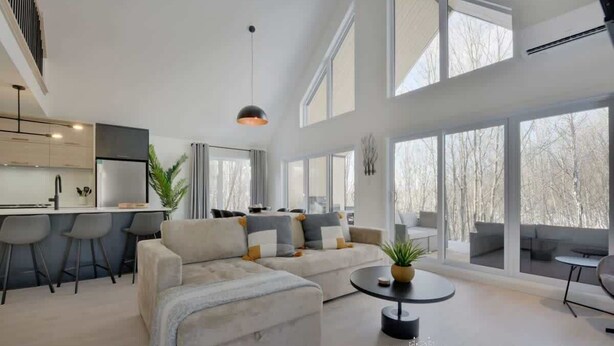 Ein modernes Interieur mit einer Couch, einem Essbereich und großen Fenstern.