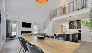 A modern open-plan living space with a dining area, kitchen, and a staircase to an upper level.