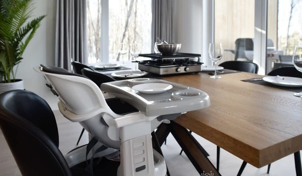 Un coin repas moderne avec une table dressée pour deux personnes, un réchaud portable et une chaise dotée d’un plateau.