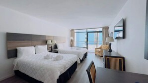 A hotel room with two beds, a desk, a chair, a TV, and a balcony with a view. - LA4 Great Studio on the beach + Pool (Myrtle Beach)