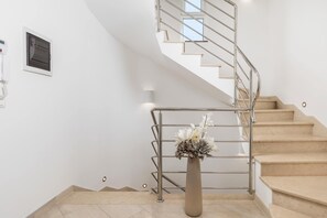 A staircase with a metal railing, a beige floor, and a vase with flowers. - Villa Luxoria (Peroj)