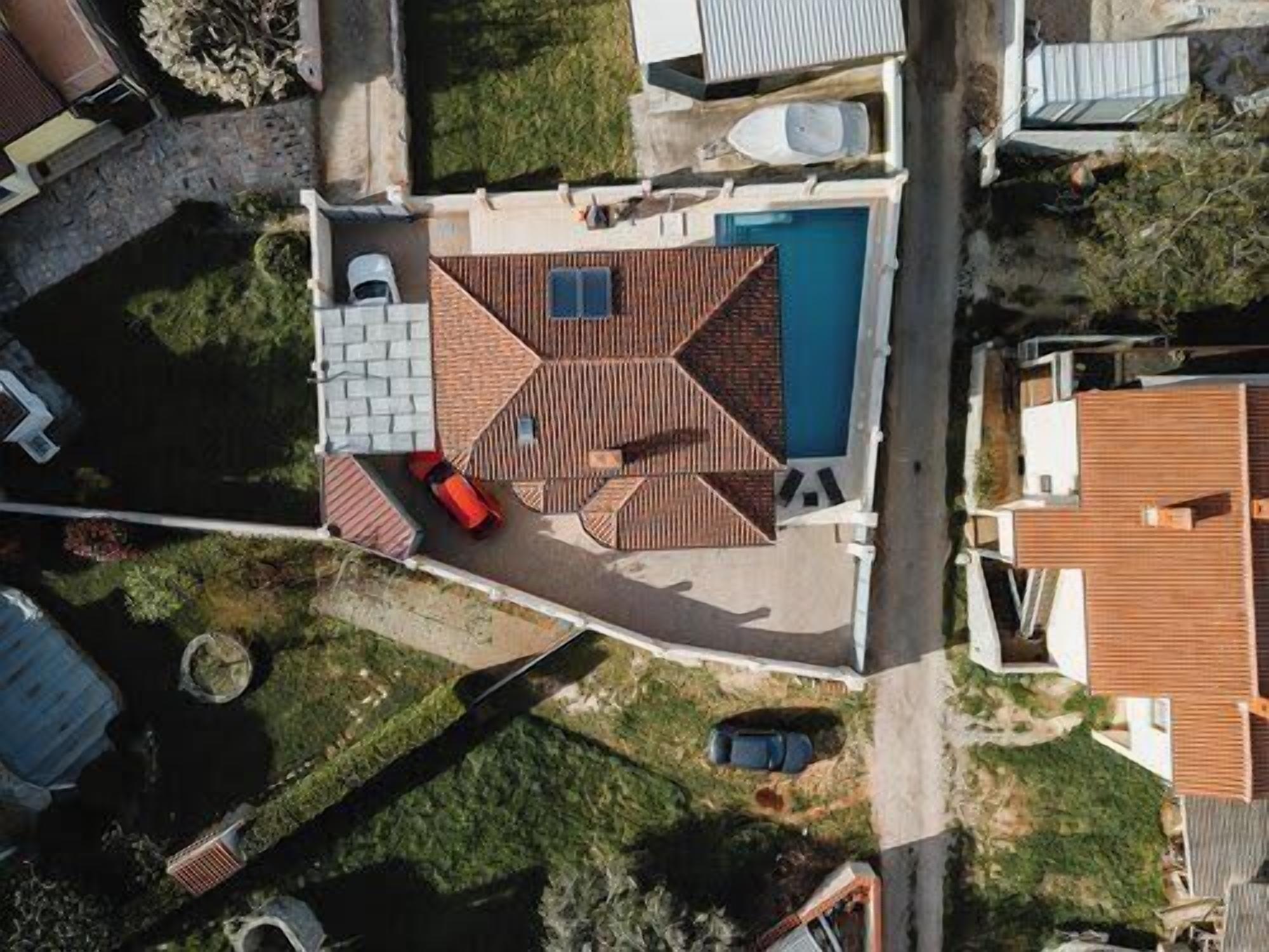 Vista aerea di una proprietà residenziale con piscina, patio e un piccolo giardino.