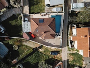 Vista aérea de una propiedad residencial con piscina, patio y un pequeño jardín.