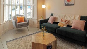 Ein Wohnzimmer mit Sofa, Sesseln, Couchtisch und einem großen Fenster.