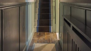 Ein Flur mit Treppe, Deckenlampe und einem gerahmten Bild an der Wand.