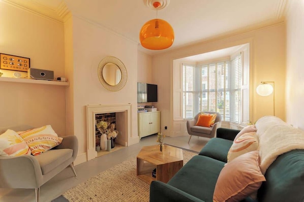 A living room with a fireplace, sofa, coffee table, and a television.