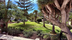 Un jardín ajardinado con varios árboles, césped bien cuidado y un sendero de piedra.