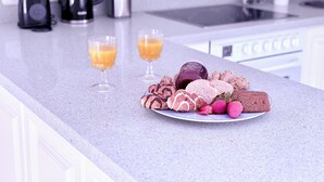 Una encimera de cocina con un plato de pasteles, dos vasos de zumo de naranja y una botella de vino.