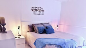 Un dormitorio moderno con cama, mesitas de noche y una obra de arte colgada en la pared.