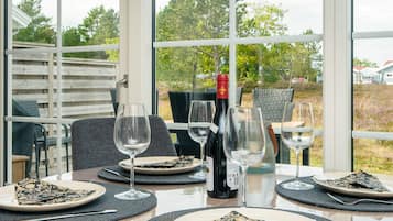 Una mesa de comedor dispuesta con platos, cubiertos y copas de vino, con una botella de vino y un vaso de agua.