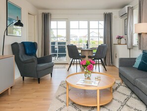 A modern living room with a sofa, armchairs, a coffee table, and a dining area with chairs and a table. - 4 Star Holiday Home in Laeso (Læsø)