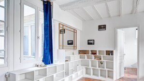 A spacious room with white shelving units, a blue curtain, and a tiled floor.