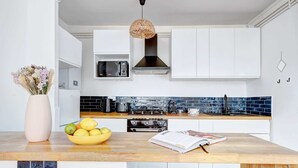 A modern kitchen with white cabinets, a black stove, and a blue-tiled backsplash.
