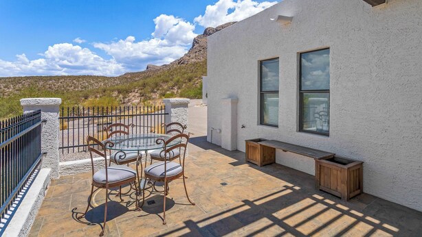 A patio with a table and chairs, a wooden bench, and a stone wall. - Foothills Casita | Summer Mountain Retreat (Oro Valley)