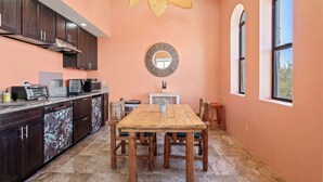A kitchen with dark wooden cabinets, a wooden dining table, and a ceiling fan. - Foothills Casita | Summer Mountain Retreat (Oro Valley)