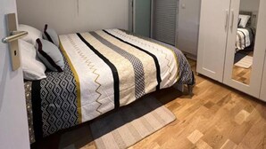 Een slaapkamer met een bed, kast en raam.