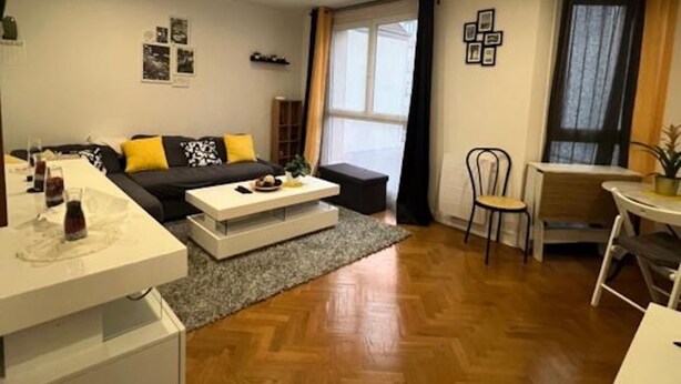 Een moderne woonkamer met een bank, salontafel en eethoek.