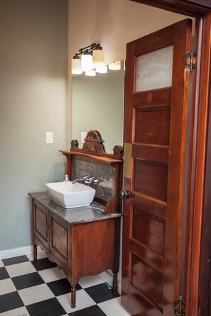 Bathroom features a classic design with a wooden door, white sink, and marble countertop.