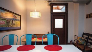 Comedor con una mesa blanca, sillas azules y una lámpara colgante.