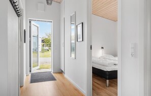 Une chambre moderne avec un lit, une table de chevet et une commode. Une porte donne accès à un balcon avec vue sur l’extérieur.