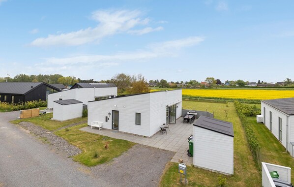 Un quartier résidentiel moderne composé de maisons individuelles, avec une allée pavée et, au loin, un champ de fleurs jaunes.