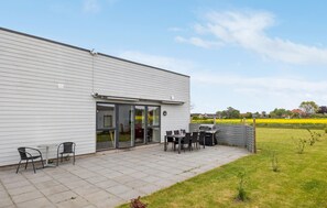 Un bâtiment moderne doté d’un patio aménagé avec des espaces de détente en plein air et un barbecue.