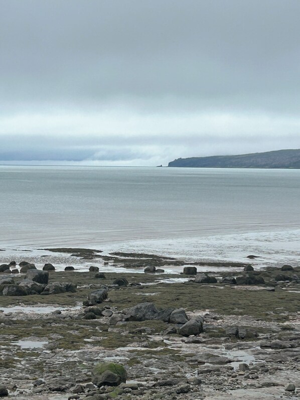 Una costa rocosa con vista al mar y tierra a lo lejos.